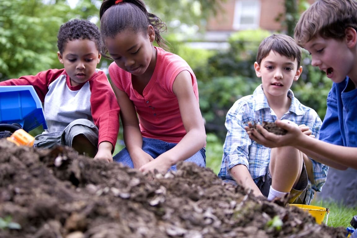 Children playing in a pile of dirt having fun 