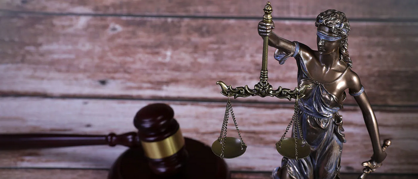 A bronze statue of Lady Justice holding a sword. A gavel is next to the statue.