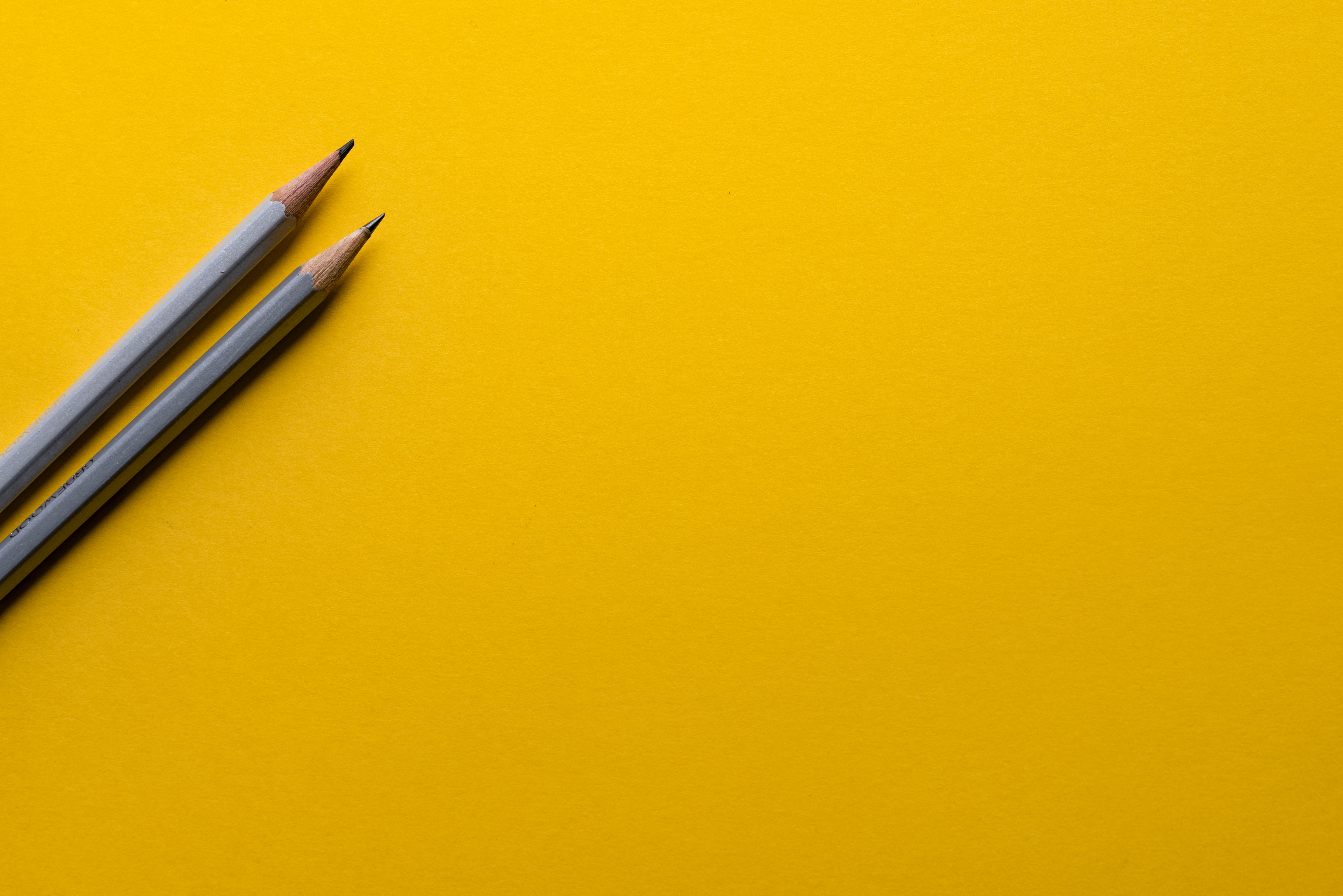 Photo of two pencils on a yellow background. 