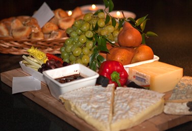 Photo shows a variety of cheeses, fruits, and breads served on a tray