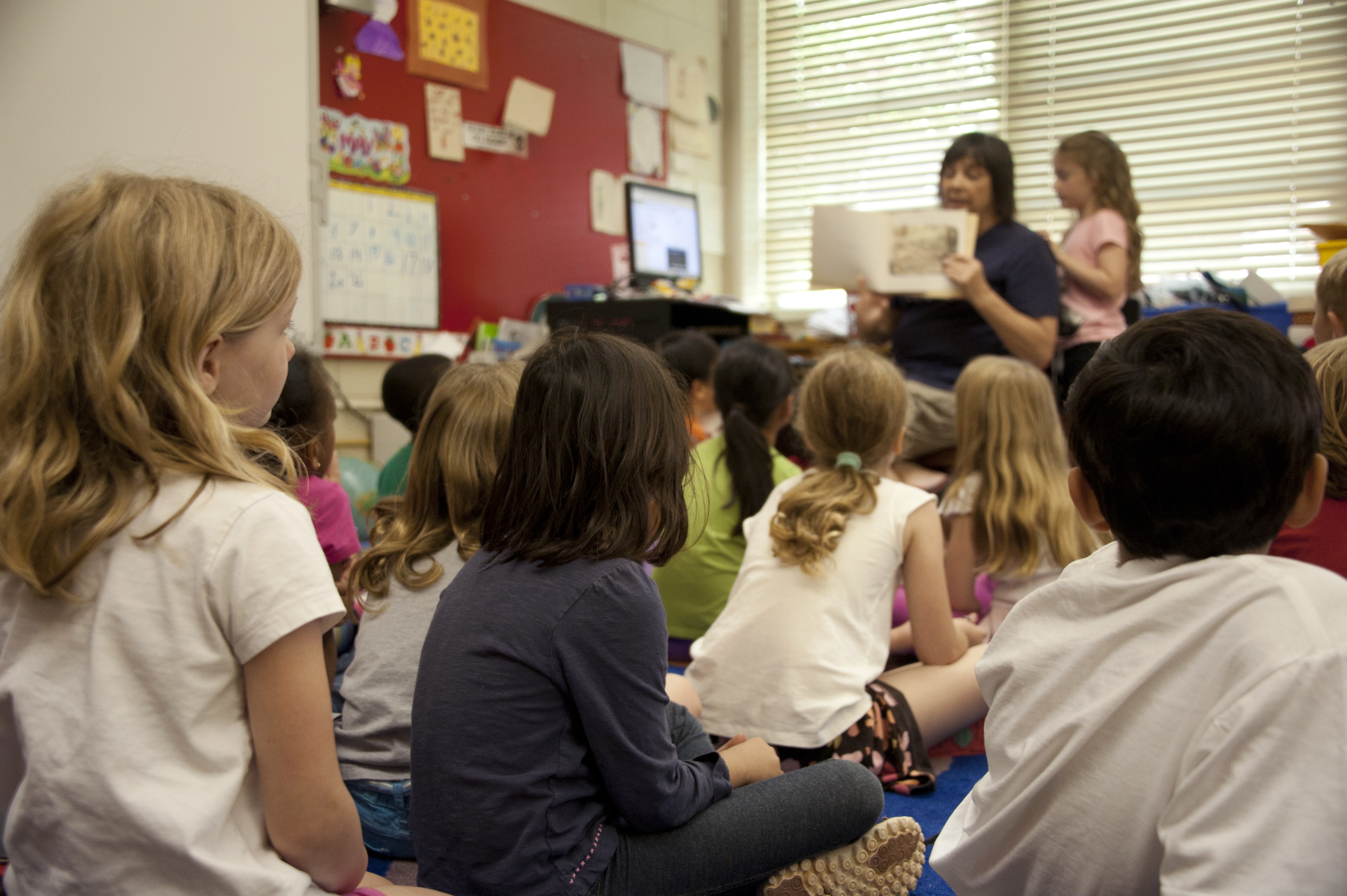 Toddler classroom with teacher reading to the class.