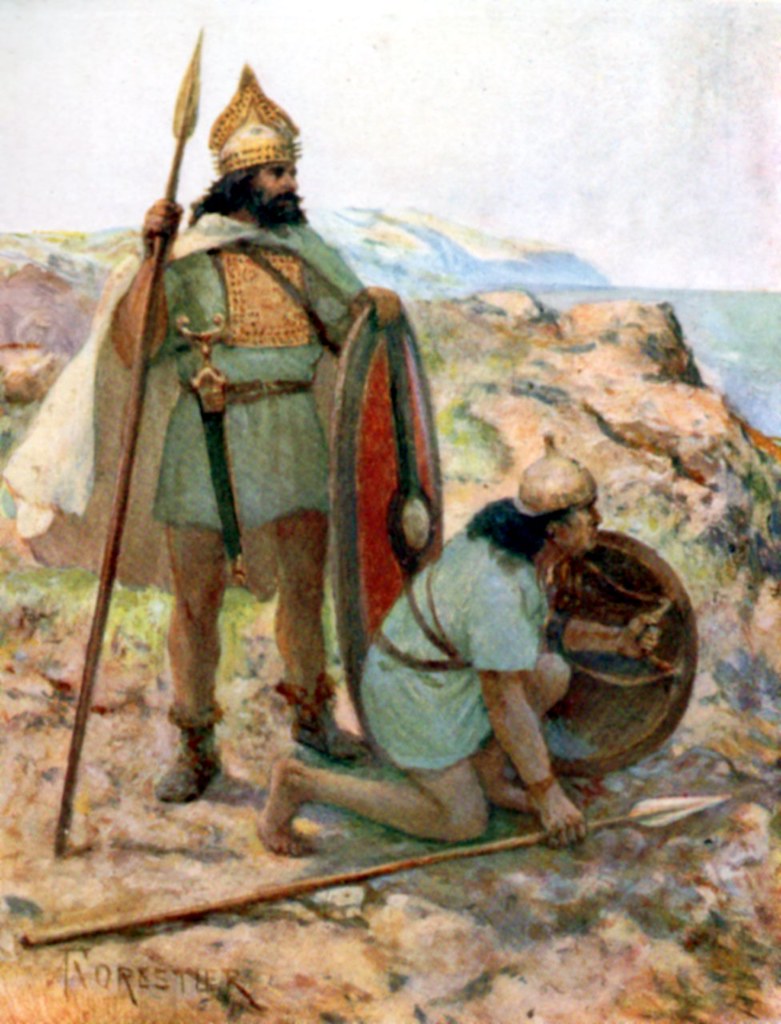 Two men dressed in tunics and bronze age armor. One is standing, one is crouching. Both are holding a spear and shield. 