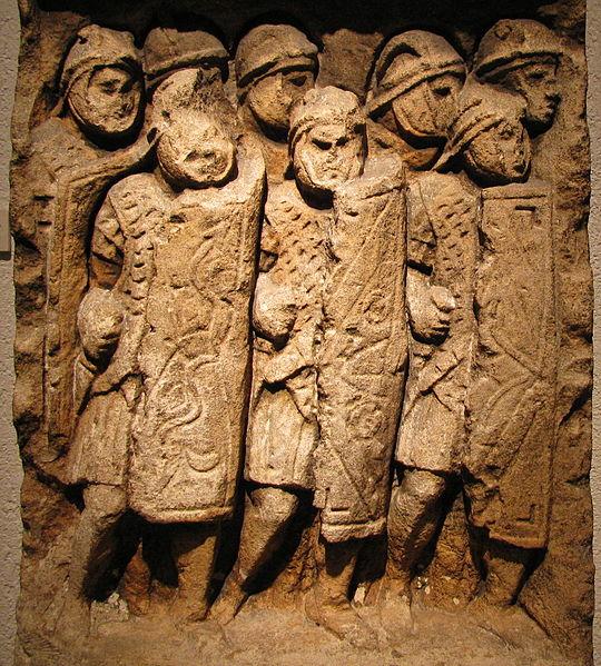 Wall carvings of a Roman legion in battle, with the characteristic large rectangular shields. A regular legionnaire would typ